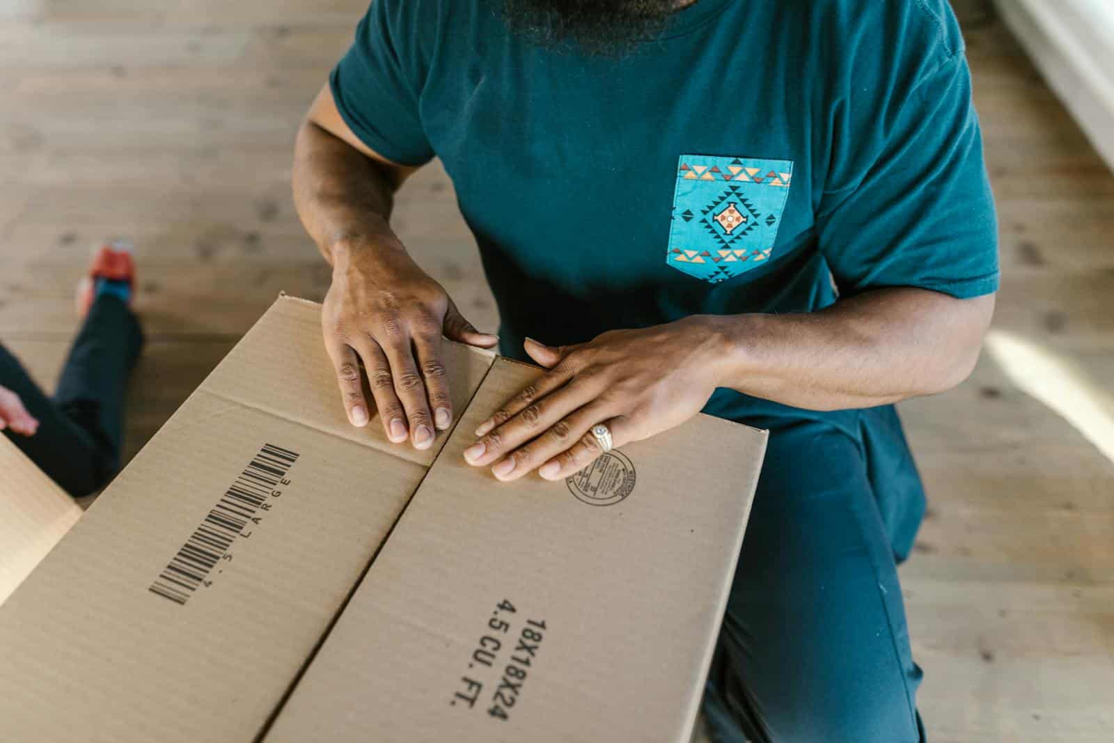 Close-up of a person sealing a cardboard box, capturing the essence of moving or packing up.